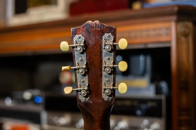 Back of the sunburst L-00 headstock with strip tuners and faint factory stamping