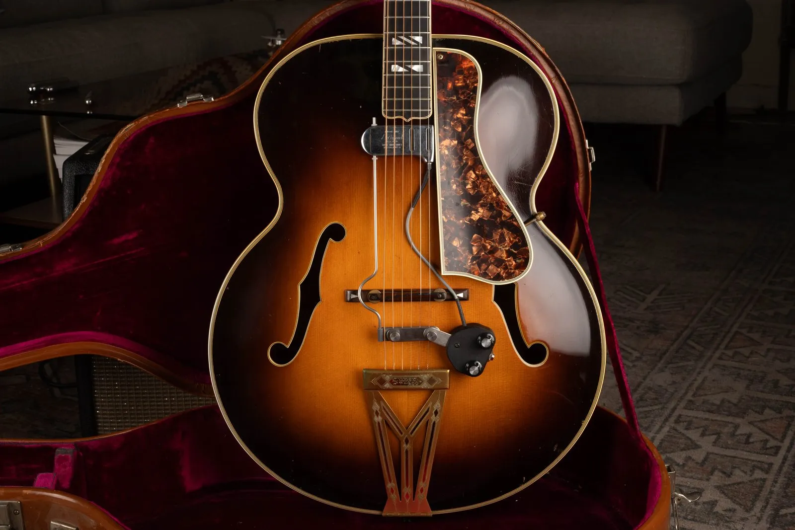 A 1938 Gibson Super 400 in sunburst with a floating DeArmond pickup, in a brown case with magenta lining.