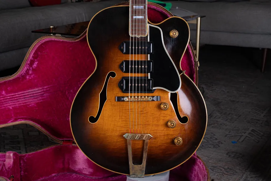 Sunburst ES-5 body with three black pickups and a large black pickguard beside a pink-lined case