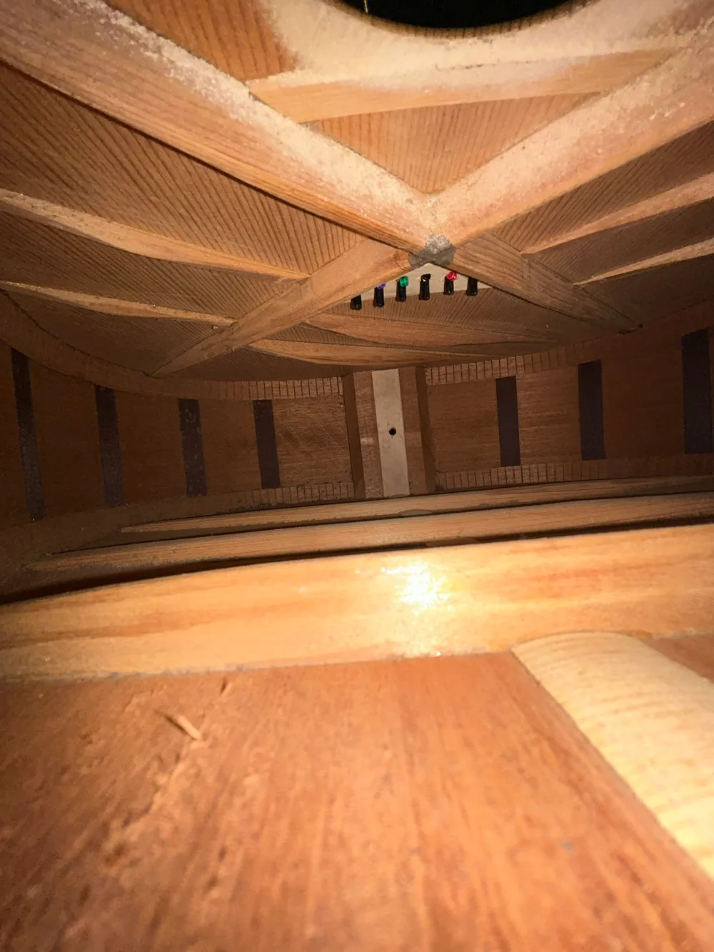 Interior of a 1955 Martin D-18 showing the soundhole edge, X crossing and bridge pins