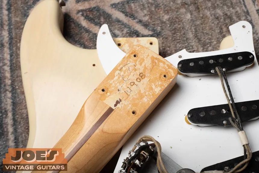Removed neck heel of a factory-refinished 1956 Fender Stratocaster, showing a burned-in serial number beside its blonde body.