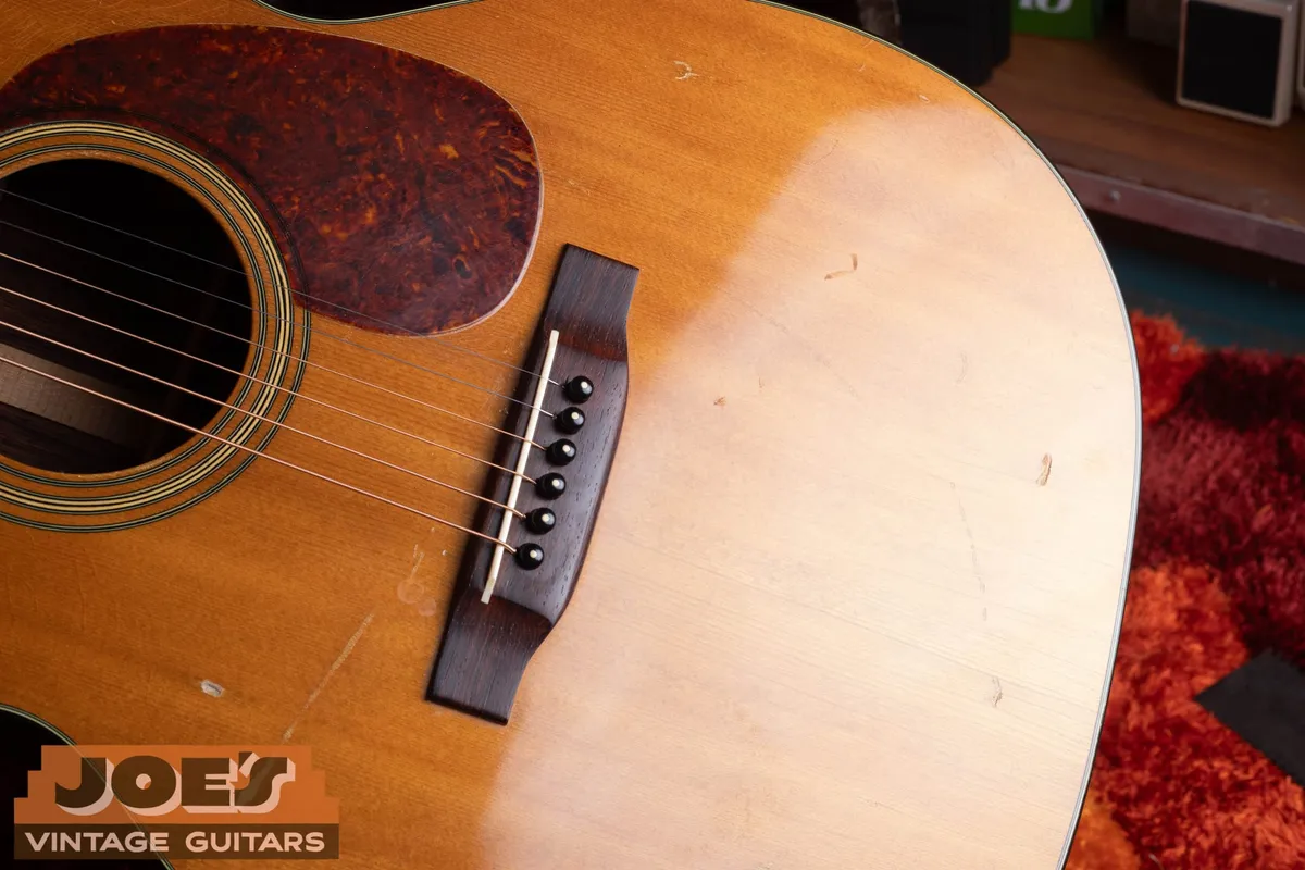 Close view of the bridge, tortoise-pattern pickguard, and play marks on the 1956 Martin 000-21