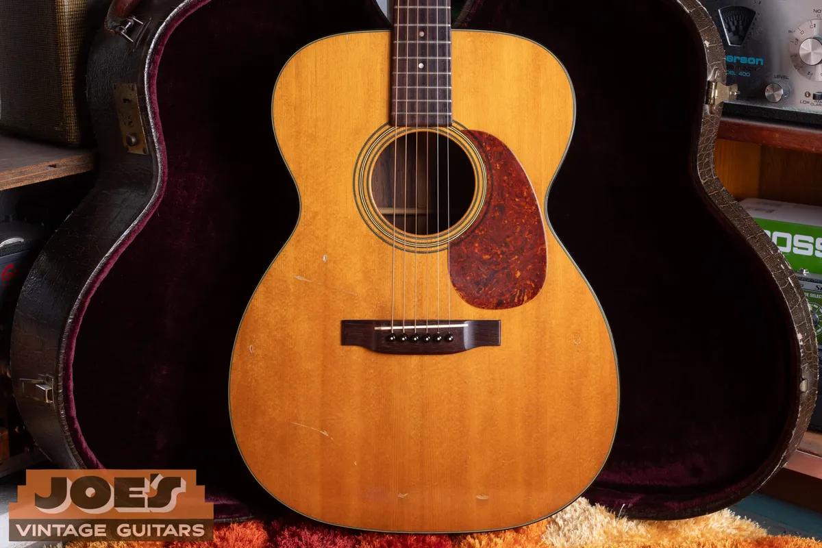 Close front view of the aged spruce top, bridge, pickguard, and soundhole of the 1956 Martin 000-21