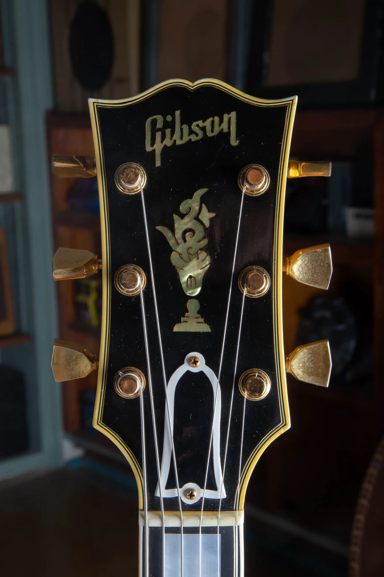 Headstock of a 1957 Gibson Byrdland showing the pearl flowerpot inlay and pearl Gibson script logo, gold tuners