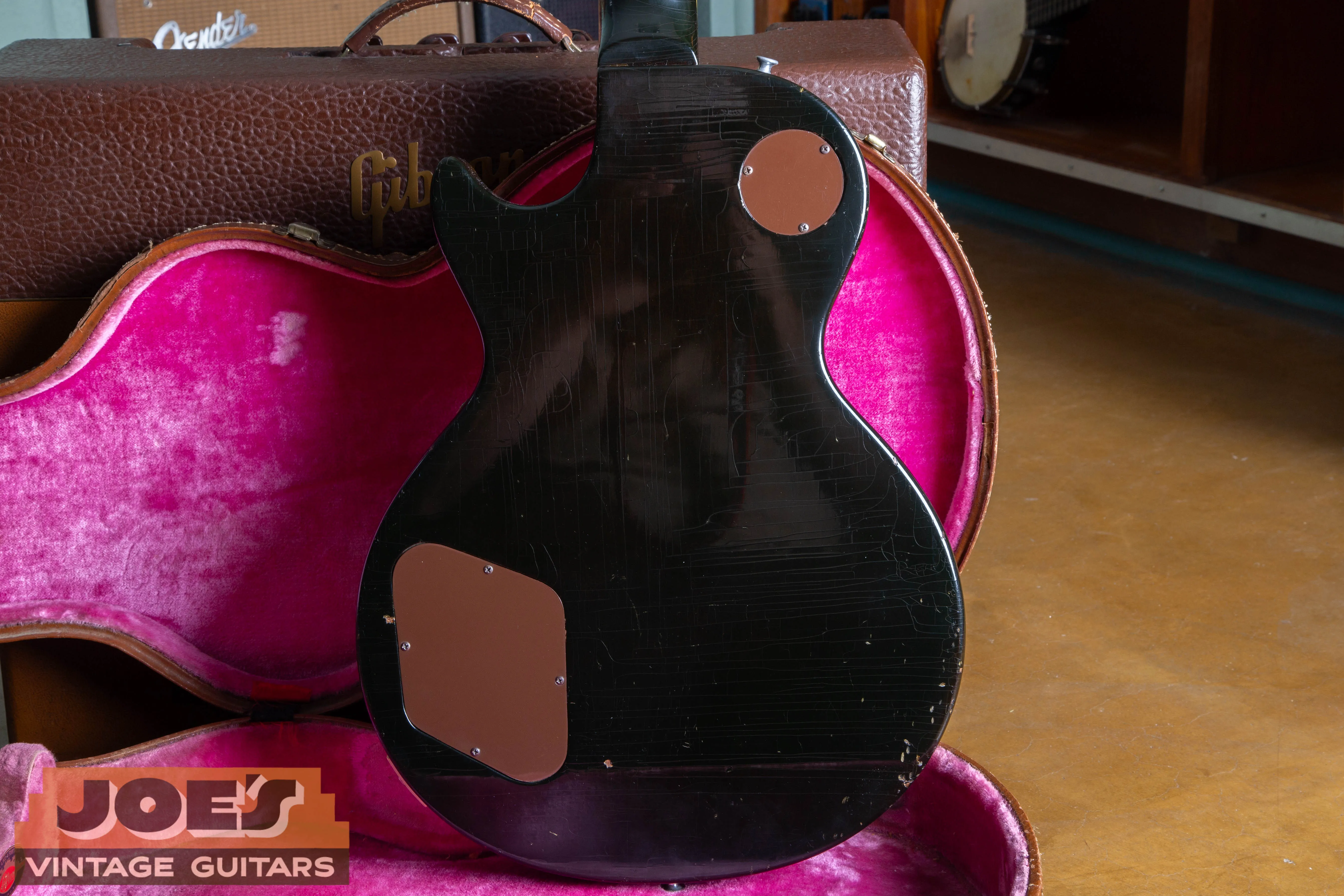 Alt TextA deep, translucent “Dark Back” finish on a 1957 Gibson Les Paul, showcasing the exceptionally dark chocolate-brown mahogany stain that allows the natural wood grain to remain subtly visible under direct light.