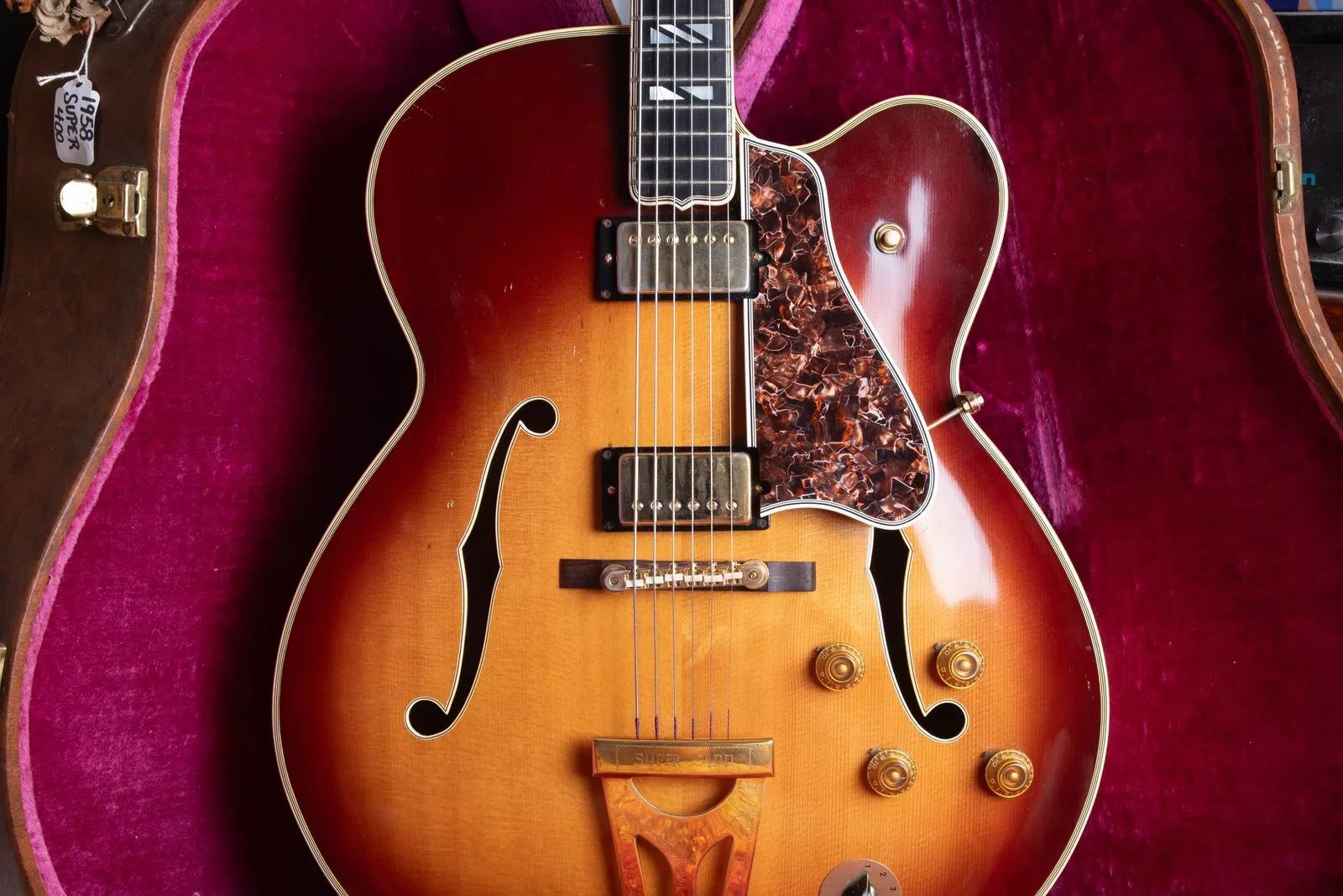 A 1957 Gibson Super 400 CES in sunburst, later factory-refinished and converted to stereo in the early 1960s, in a magenta-lined case.