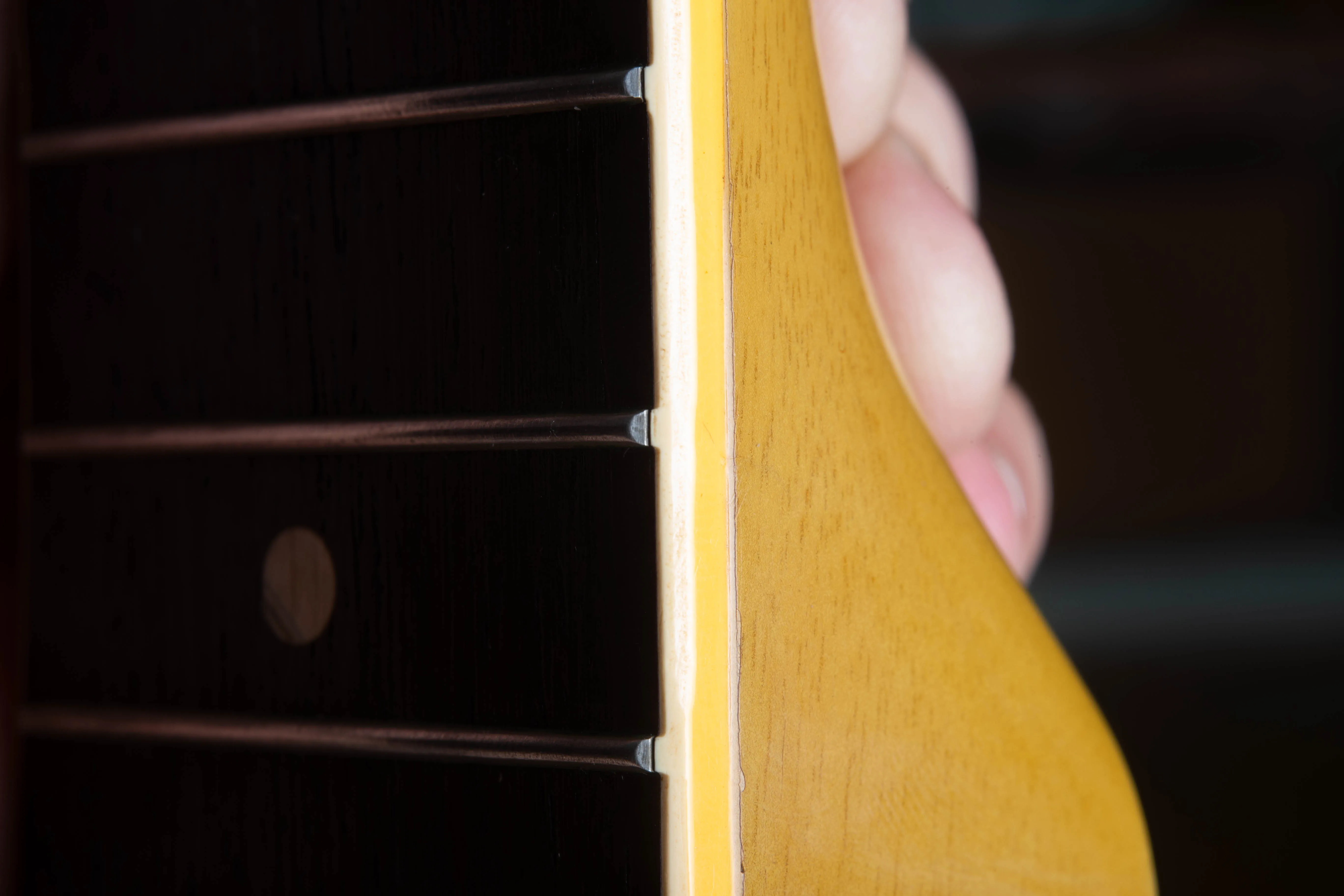 Detailed side-profile view of the neck binding on a 1958 Gibson Les Paul Special. The image shows the original “fret nibs,” where the plastic binding material rolls up to cover the ends of the frets. This feature confirms the instrument has its factory-original frets, as the nibs are typically lost during a professional refret.