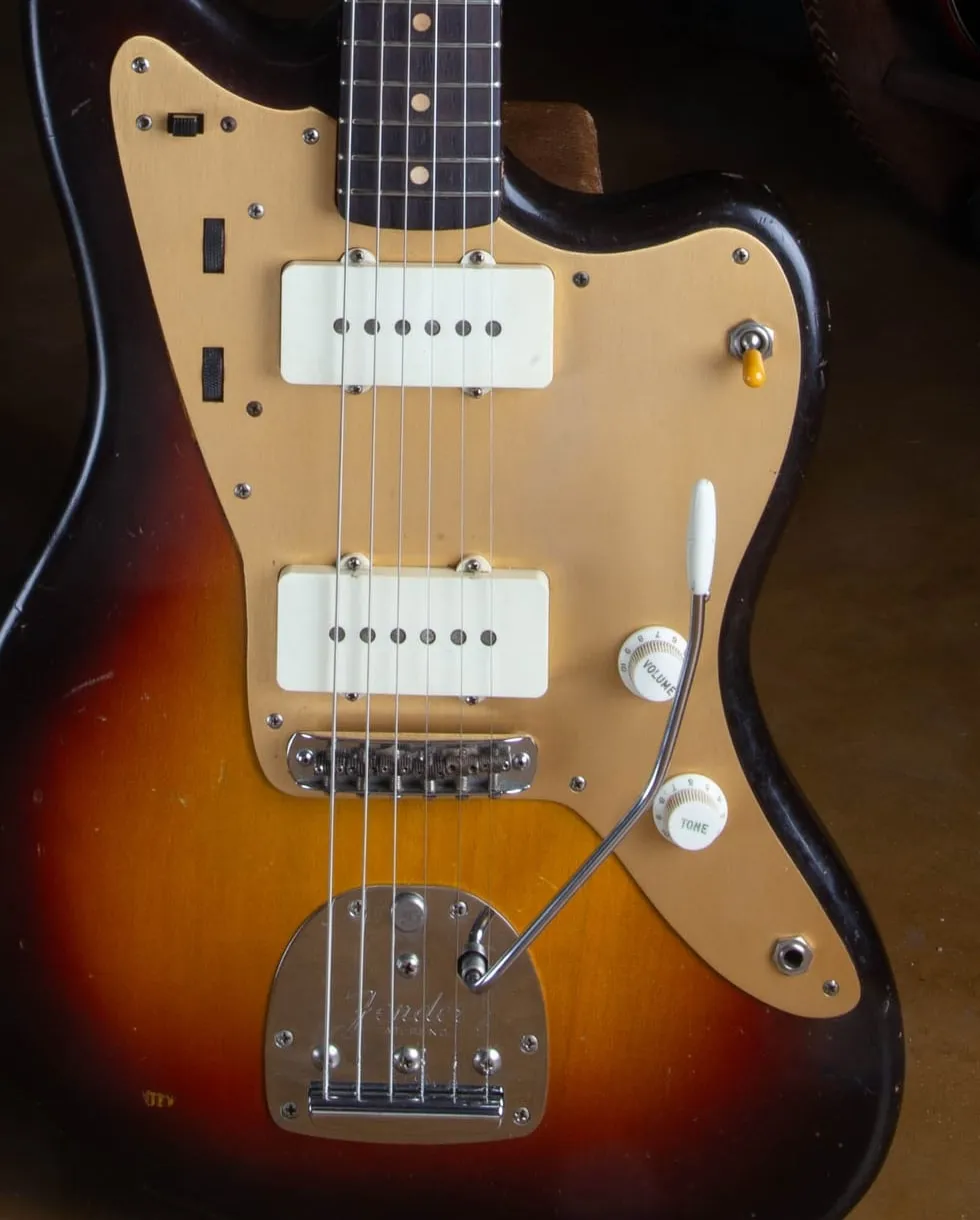 The complete gold anodized aluminum pickguard on a 1959 Fender Jazzmaster, with all nine mounting screws in view