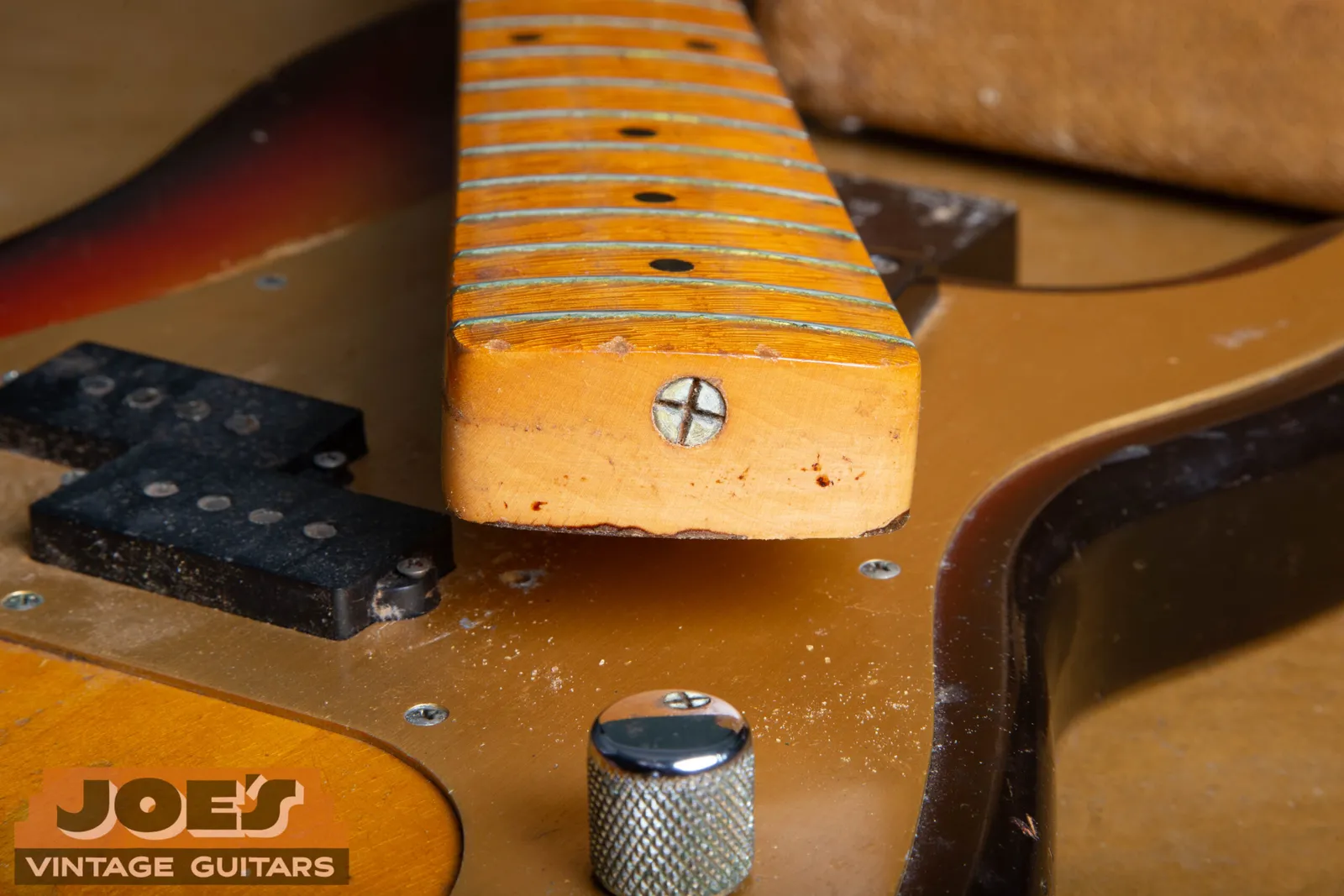 The neck of a 1959 Fender Precision Bass lifted out of the body, showing the truss rod adjuster screw recessed into the end of the heel