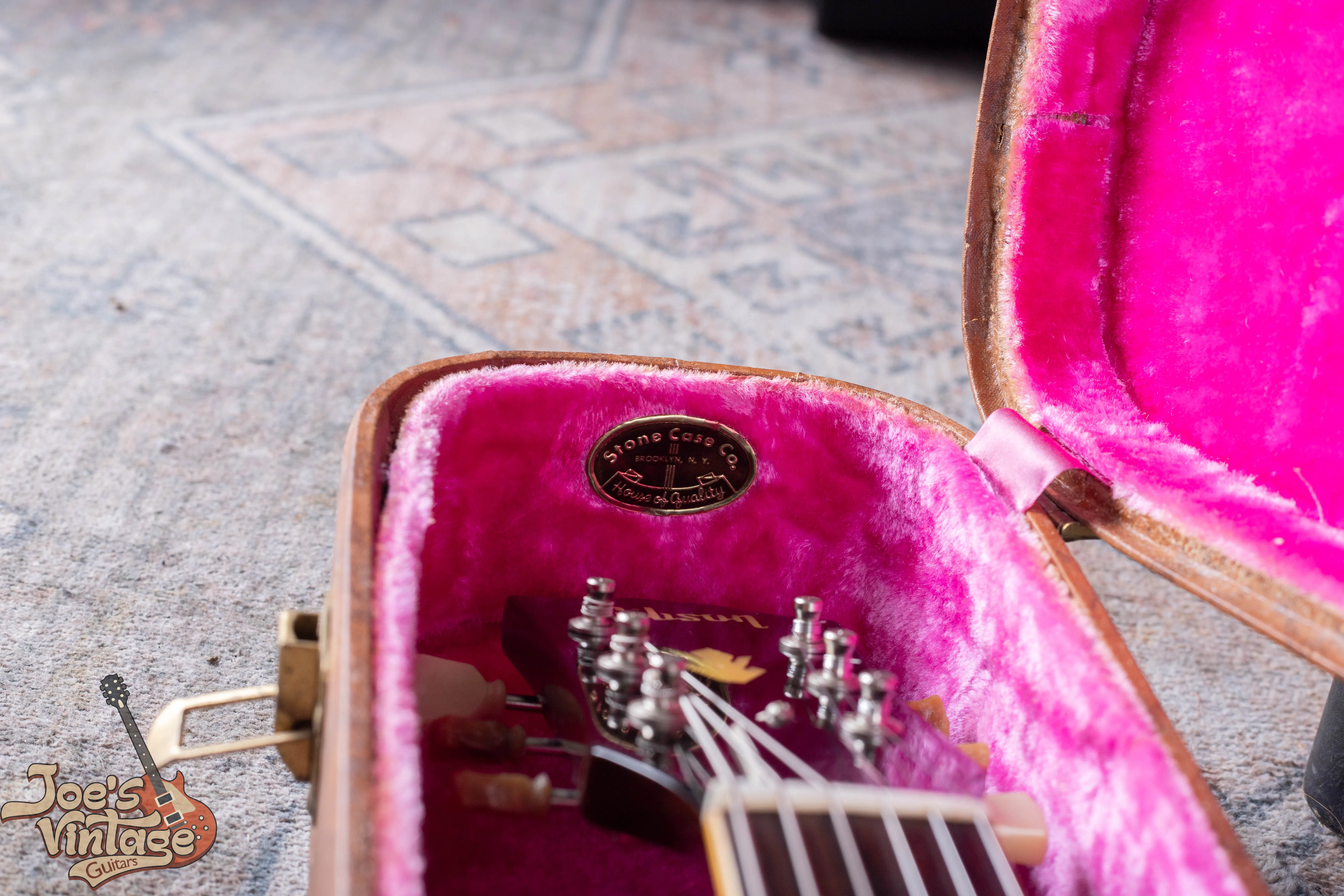 Pink-lined brown guitar case with a Stone Case Company badge beside an ES-335 headstock