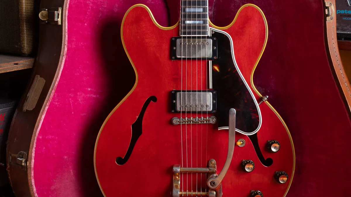 1959 Gibson ES-355 in cherry with a gold Bigsby, resting in a pink-lined brown case on the bench at Joe's Vintage Guitars in Mesa.