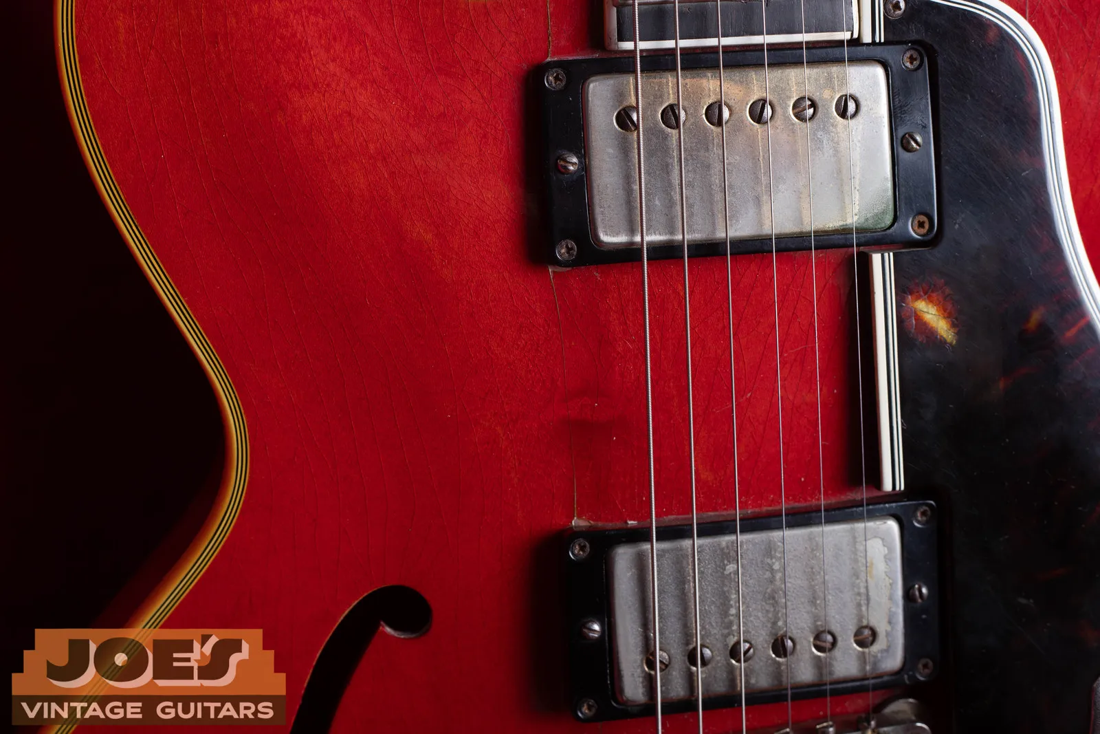 Close-up of two worn gold-cover humbuckers and a tortoise pickguard on a 1959 Gibson ES-355 in cherry.