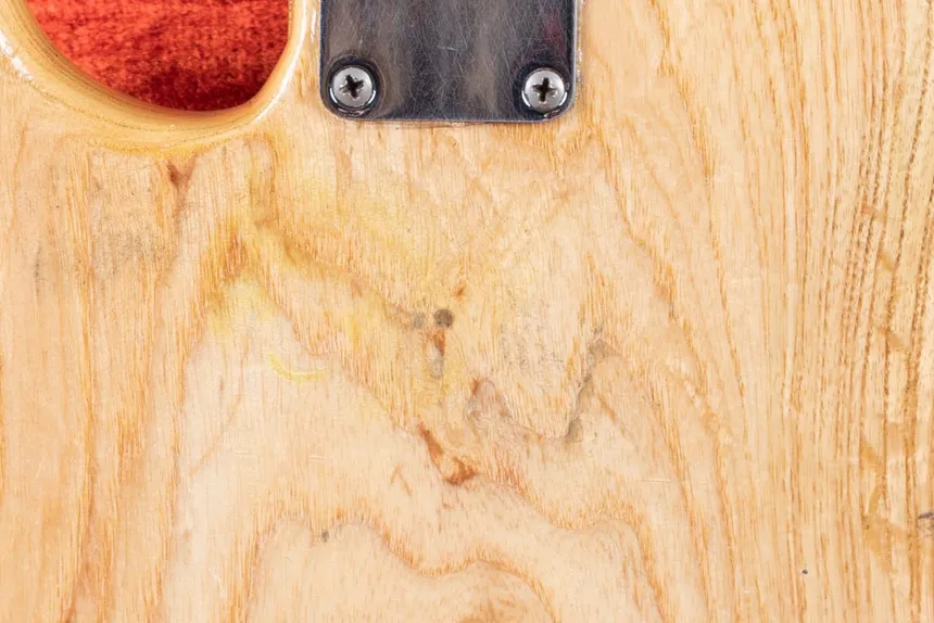 Back of a natural-refinished 1960 Fender Precision Bass, showing a small circular router dowel in the ash below the neck plate.