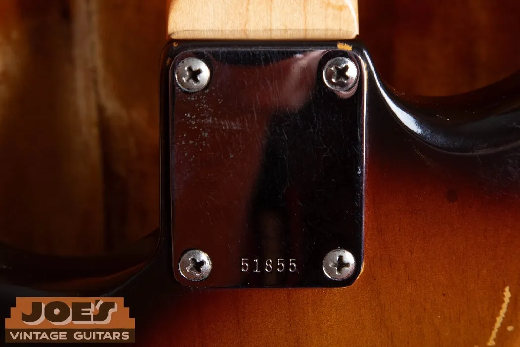 The plain chrome four-bolt neck plate of a 1960 Fender Stratocaster with a five-digit serial number