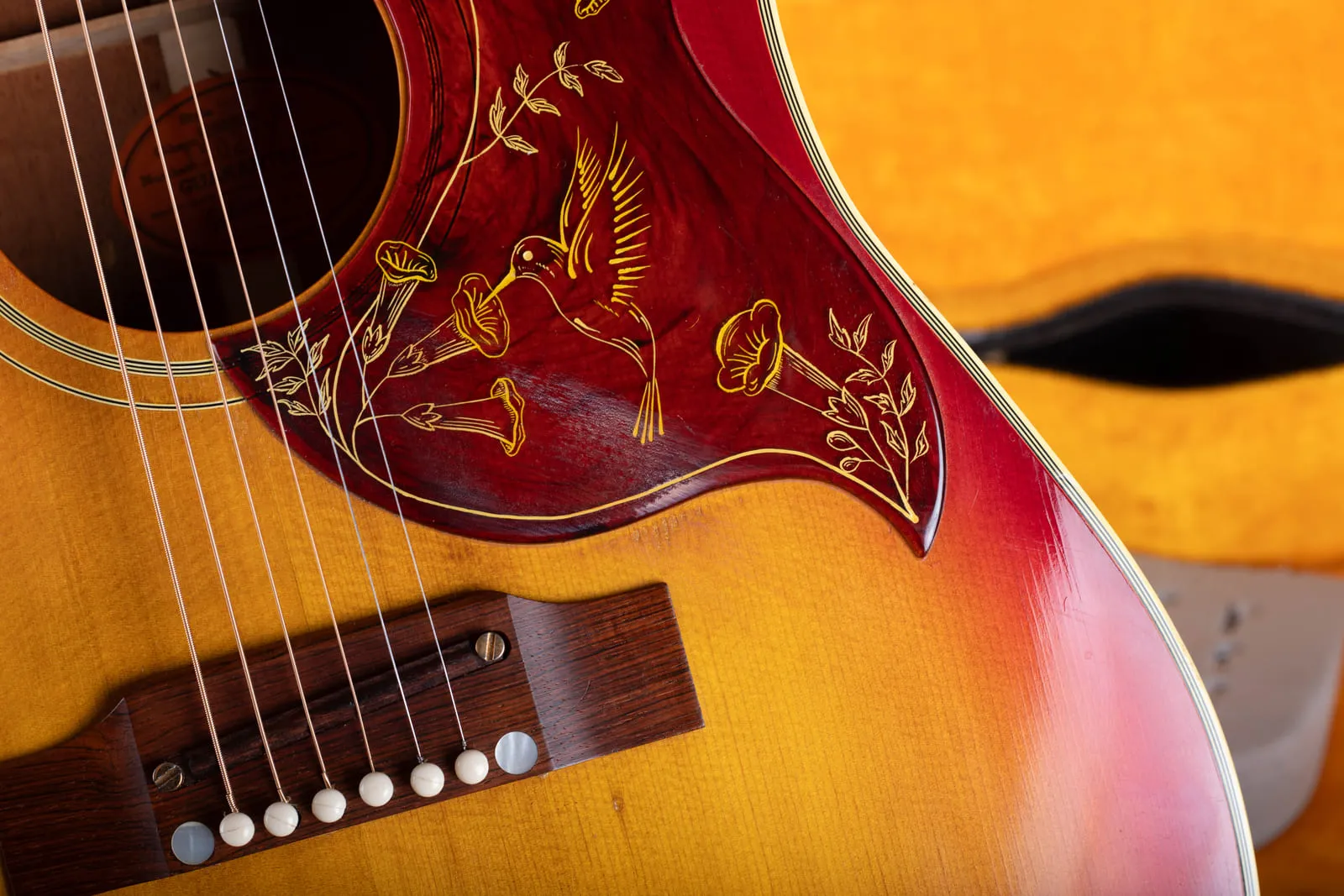 Close up of the adjustable rosewood bridge on a 1960s Gibson Hummingbird showing the rosewood saddle riding on two slotted height adjustment screws.