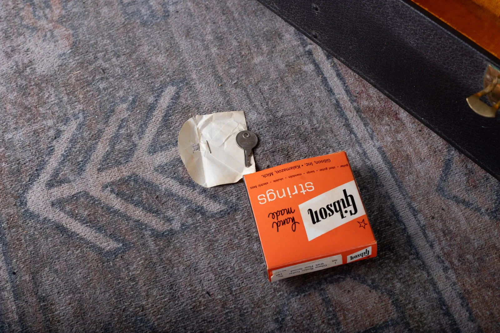Original Gibson strings box and case key on the floor of a vintage Gibson Hummingbird case, the original case candy that came with the guitar.