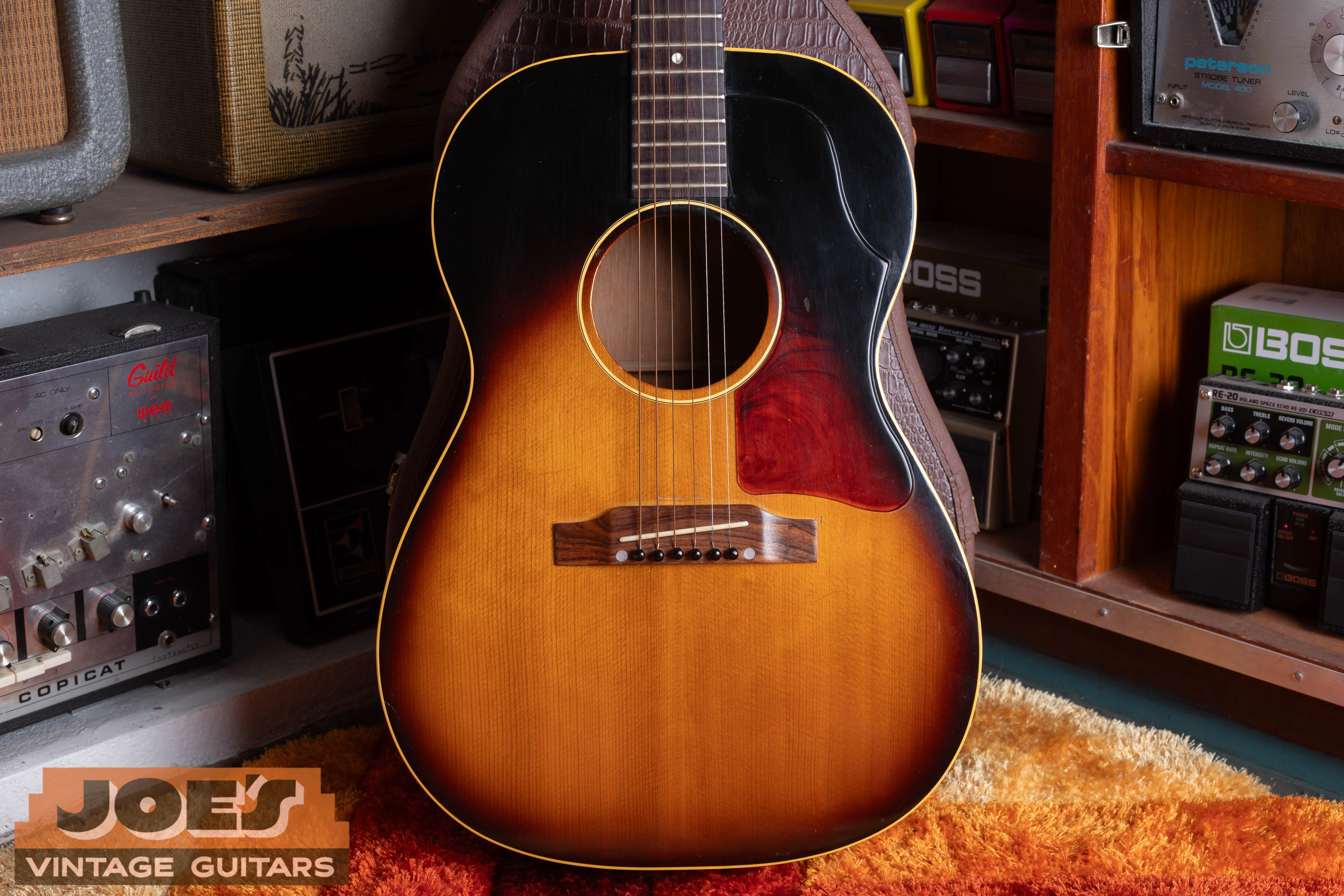 Sunburst LG-1 with a broad wood bridge and red mottled pickguard