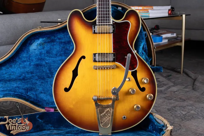 Front of a 1961 Epiphone Sheraton in sunburst with mini-humbuckers and a Bigsby vibrato, lying in its original blue-lined case. We buy vintage Epiphone guitars nationwide at Joe's Vintage Guitars.