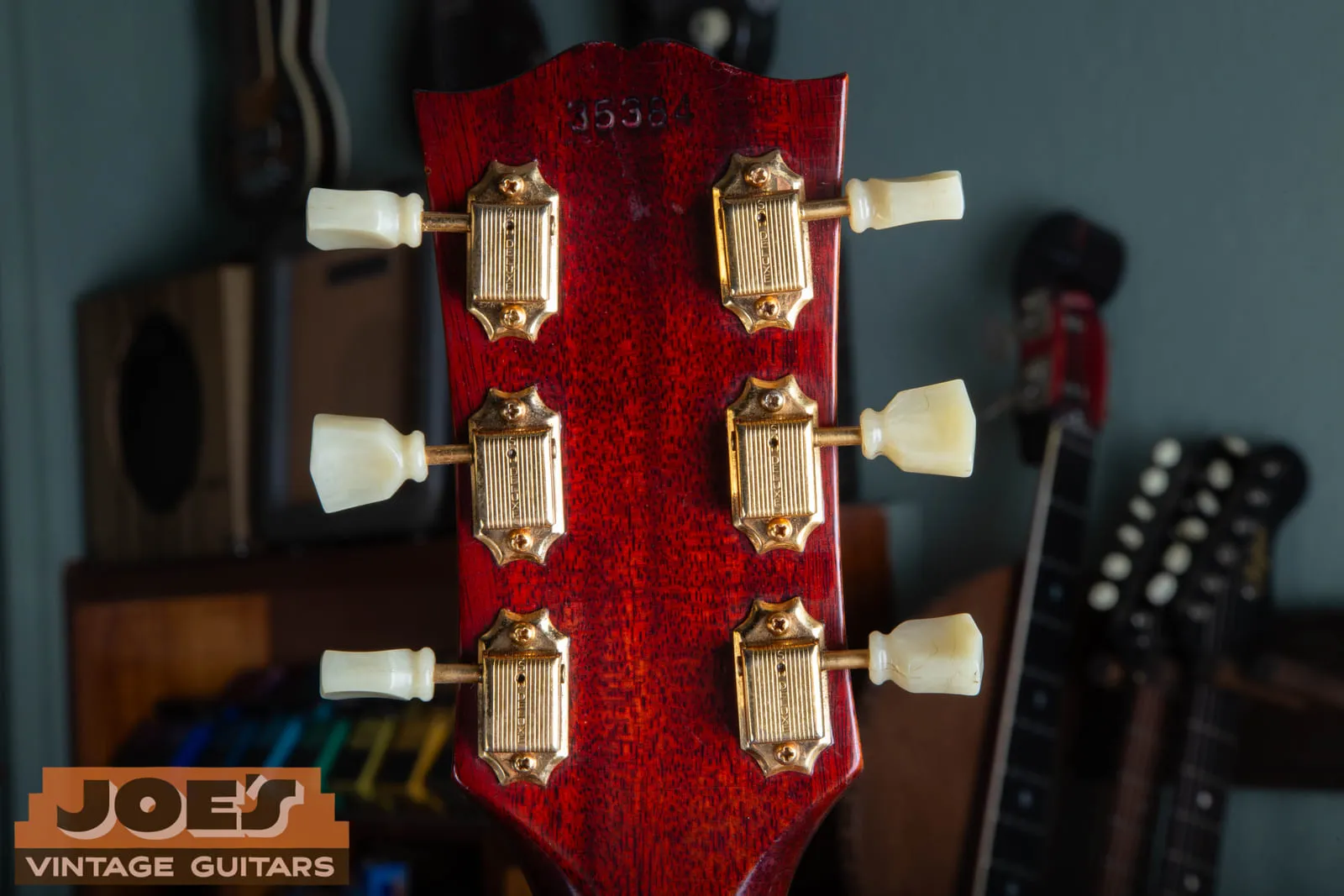 Back of the headstock of a 1961 Gibson Hummingbird showing the ink stamped serial number 35384 above gold Kluson tuners with white plastic buttons.