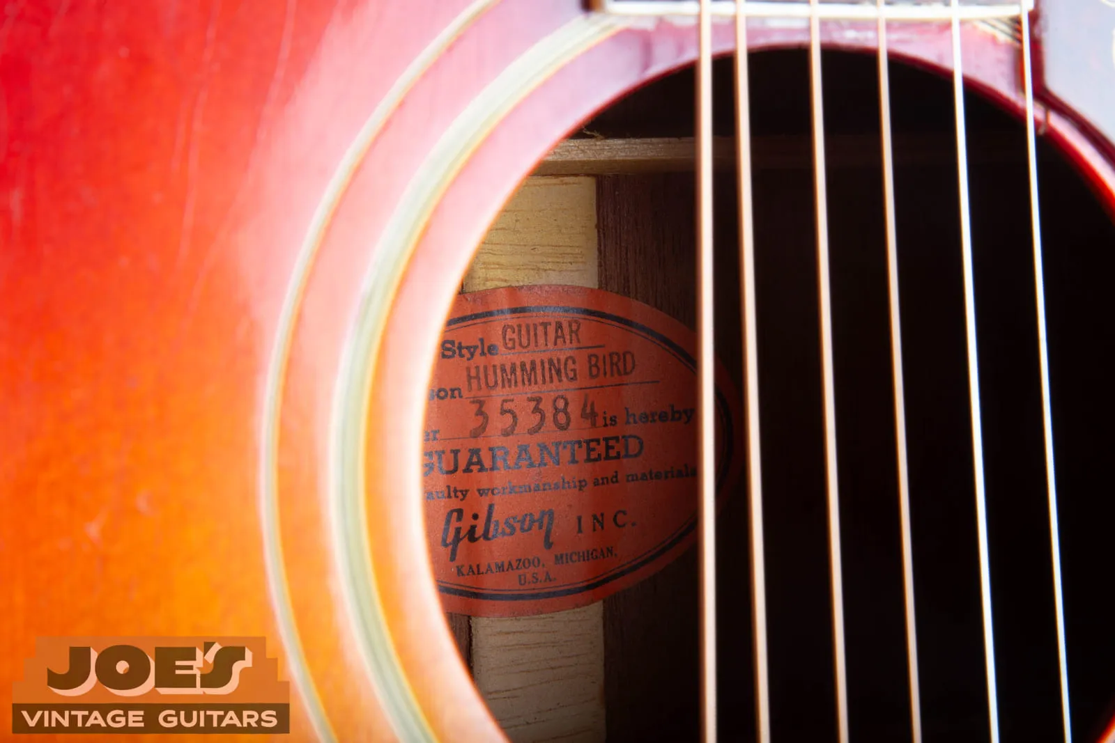 The orange oval Gibson label inside a 1961 Hummingbird, reading Style Guitar Humming Bird, number 35384, guaranteed, Gibson Inc, Kalamazoo Michigan.