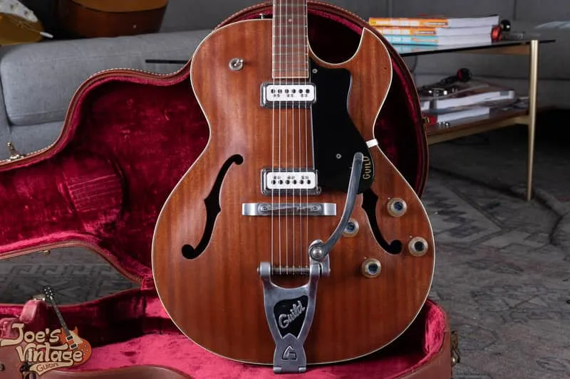 Natural-finish 1962 Guild Starfire III beside its open red-lined case, showing the body binding and f-holes.