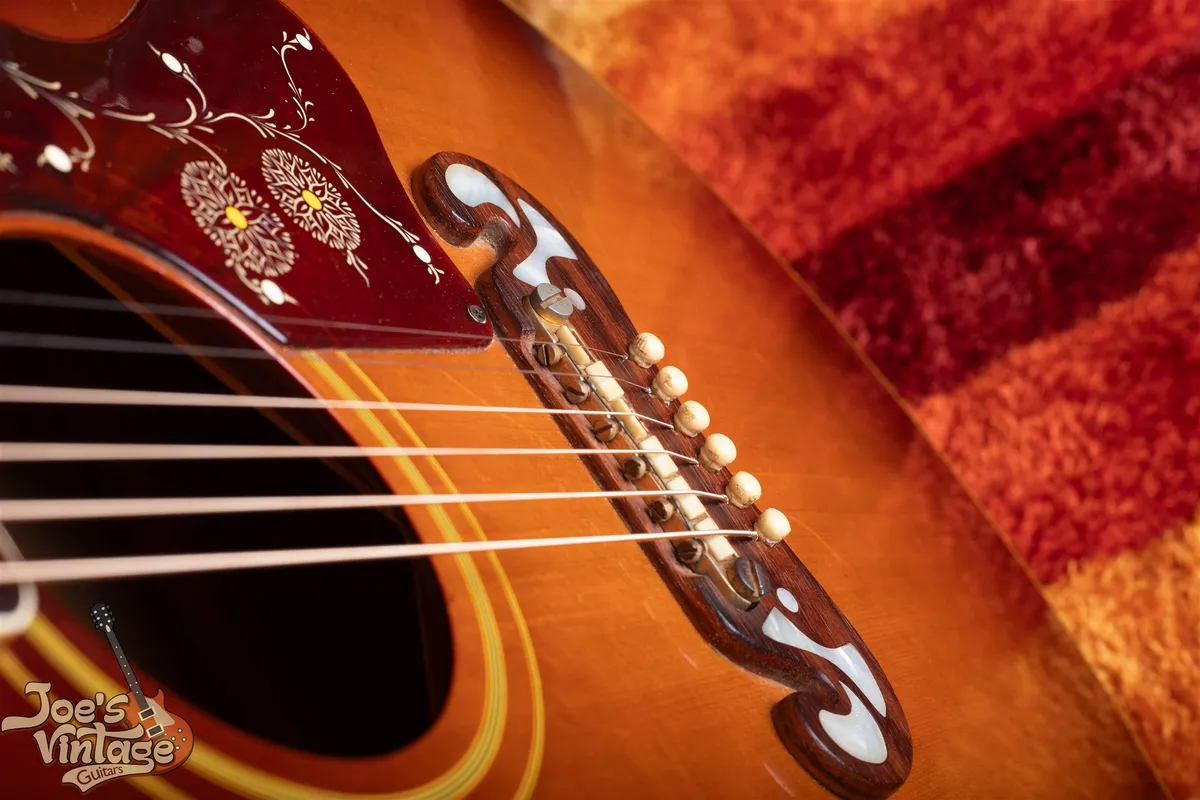 Close view of the metal Tune-o-matic saddle on a 1962 Gibson J-200 closed moustache bridge