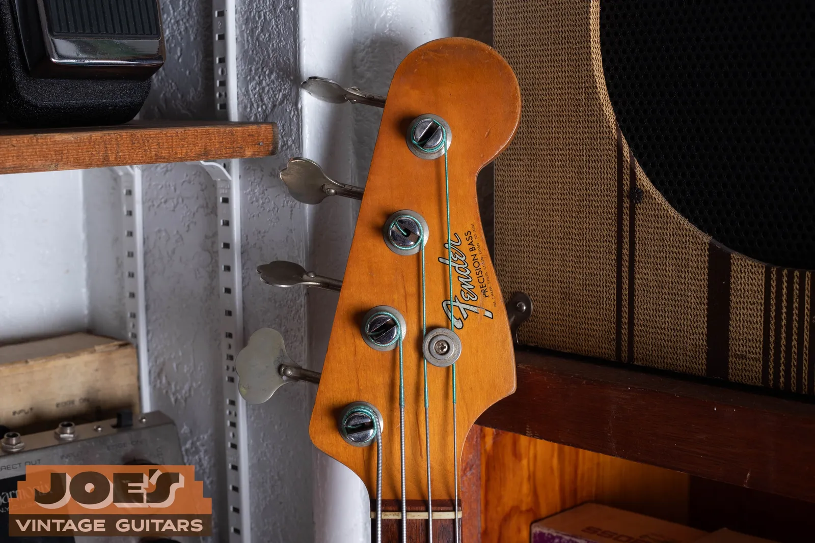 The headstock of a 1964 Fender Precision Bass showing the heavier silver transition logo with patent numbers printed below the model name