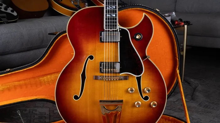 A 1964 Gibson Super 400 CES with a sharp Florentine cutaway, two pickups, and a Super 400 tailpiece, in an orange-lined case.
