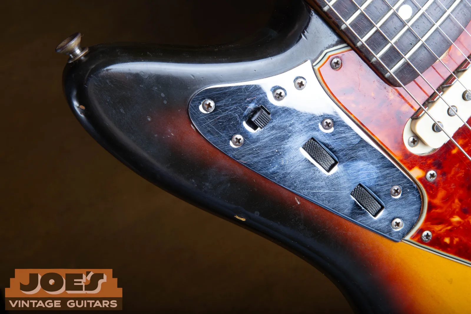The upper bout rhythm circuit slider switch and the two roller knobs for volume and tone on a 1965 Fender Jaguar