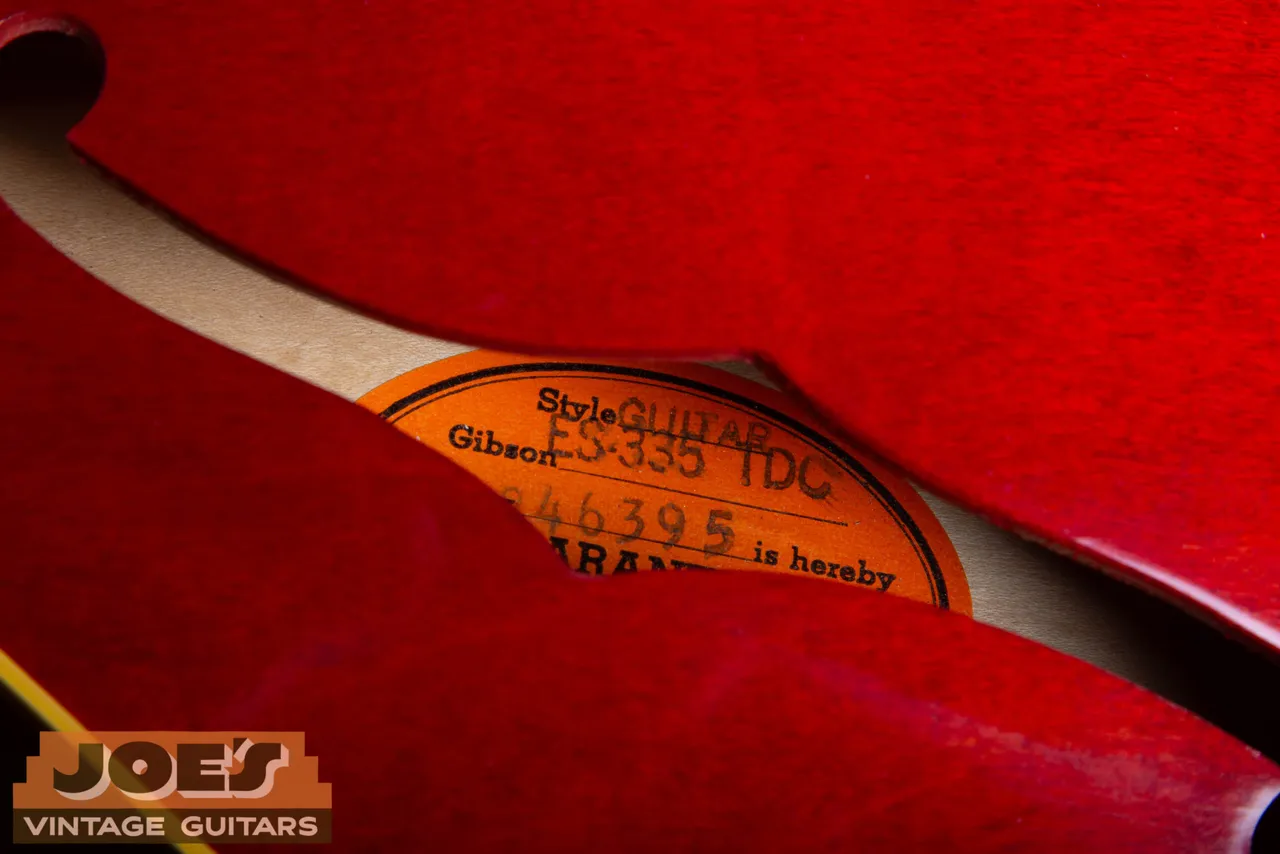 Orange Gibson paper label visible through the F hole of a red guitar