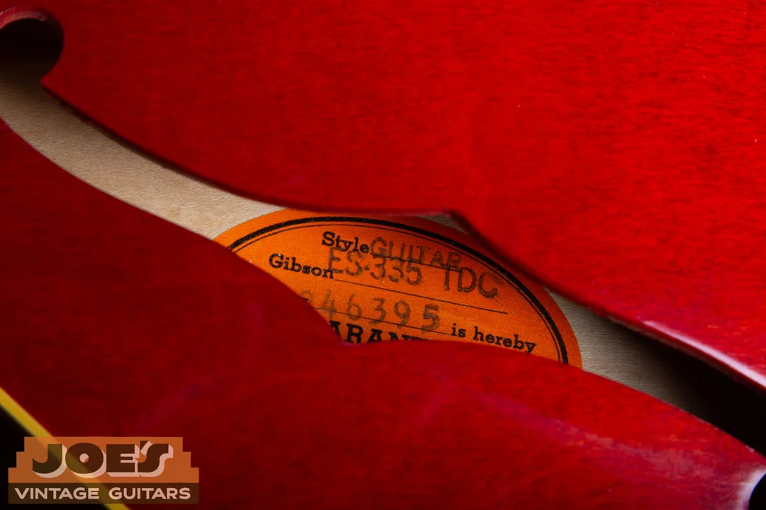 Partly obscured orange Gibson label inside a cherry ES-335 showing the style field and part of the serial field