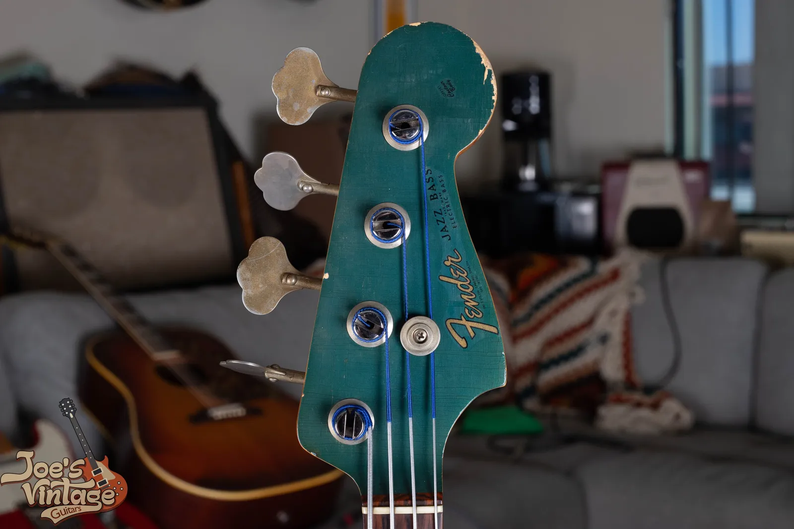 The matching painted headstock of a 1966 Fender Jazz Bass in Lake Placid Blue with the same gold Fender Jazz Bass logo
