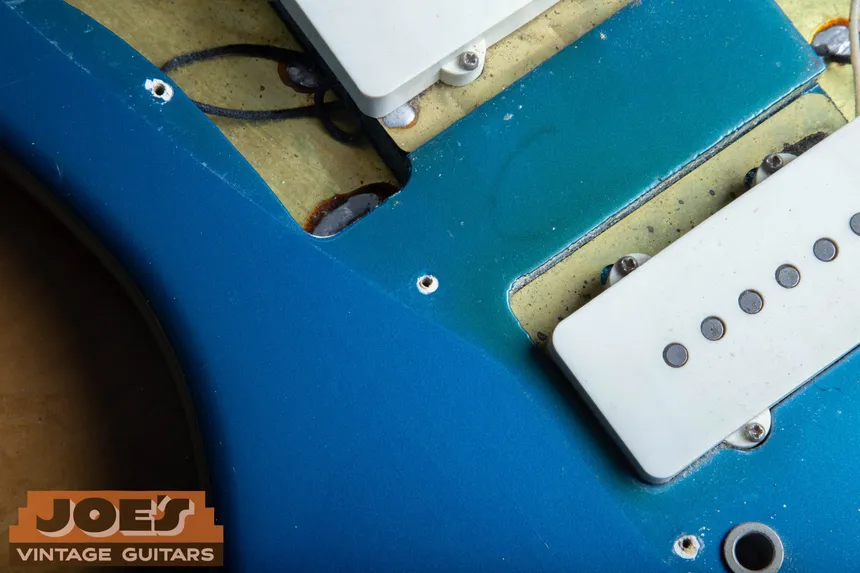 Lake Placid Blue 1966 Fender Jazzmaster with its pickguard lifted, exposing thin blue coverage and yellow sealed wood around the pickup routes.