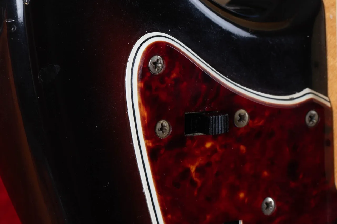 The cut edge of a multi-ply tortoiseshell Fender Jazzmaster pickguard showing tortoiseshell, white, black and white layers