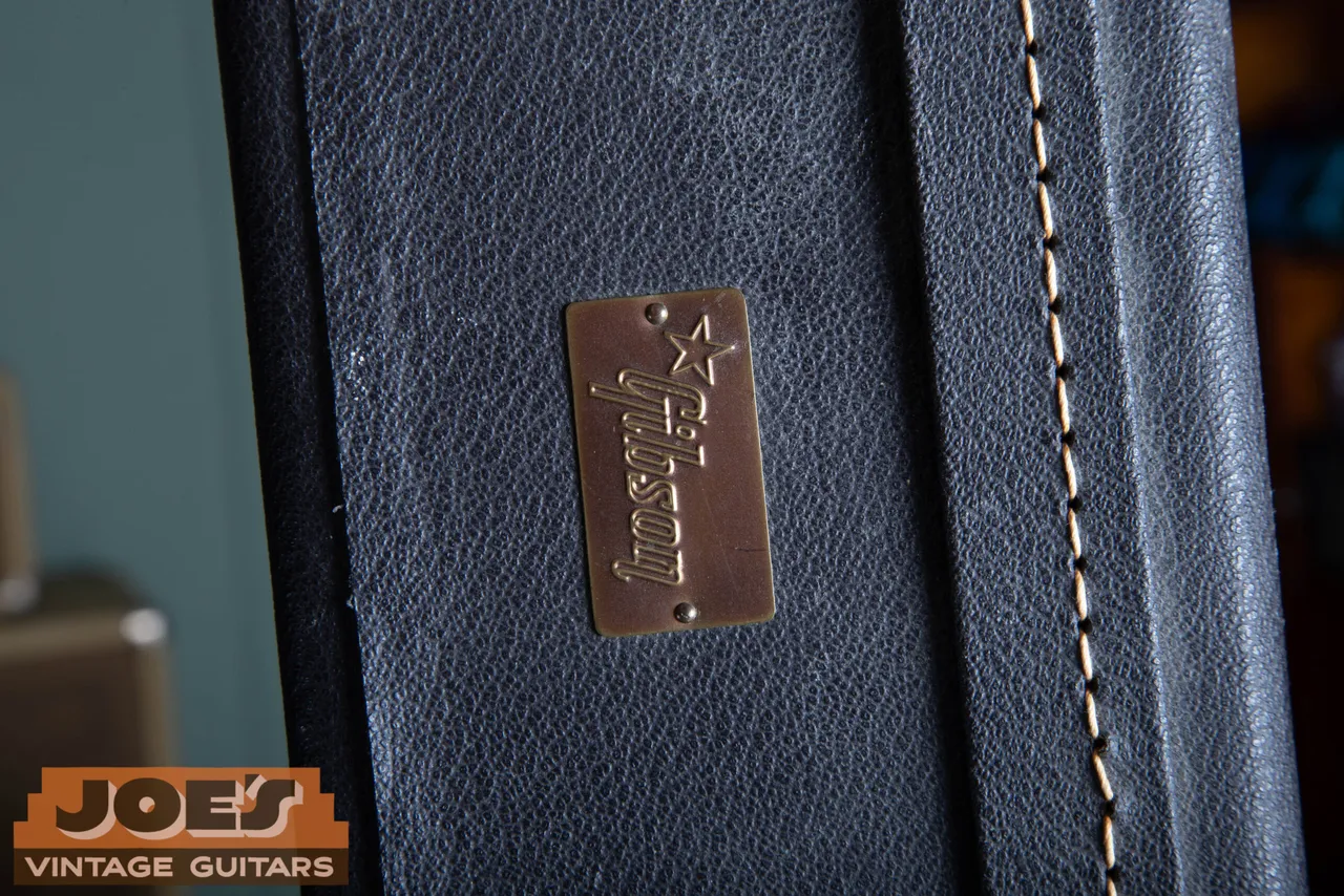 Metal Gibson badge riveted to a black guitar case