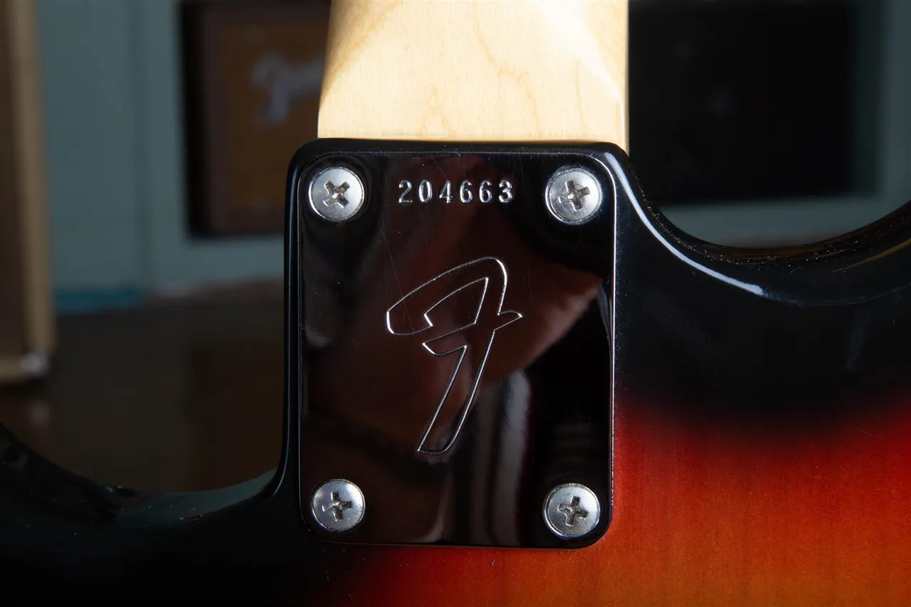A 1967 Fender big-F neck plate with a six-digit serial number stamped above a large stylized F