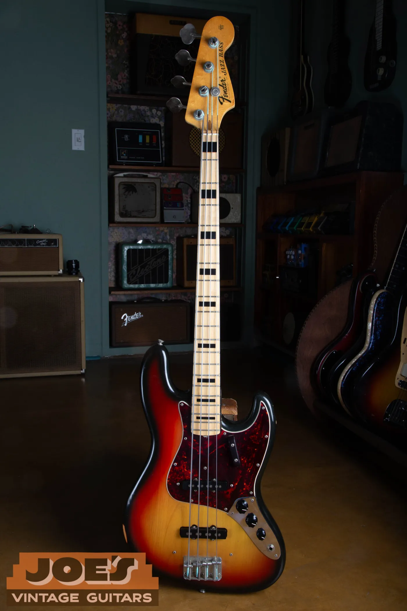 Full front view of a 1973 Fender Jazz Bass in sunburst with a maple neck, black block inlays and a black pickguard