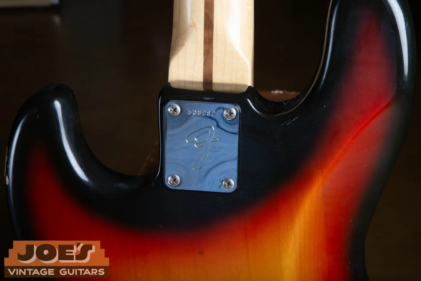 The neck plate of a 1973 Fender Jazz Bass showing the stamped serial number on chrome