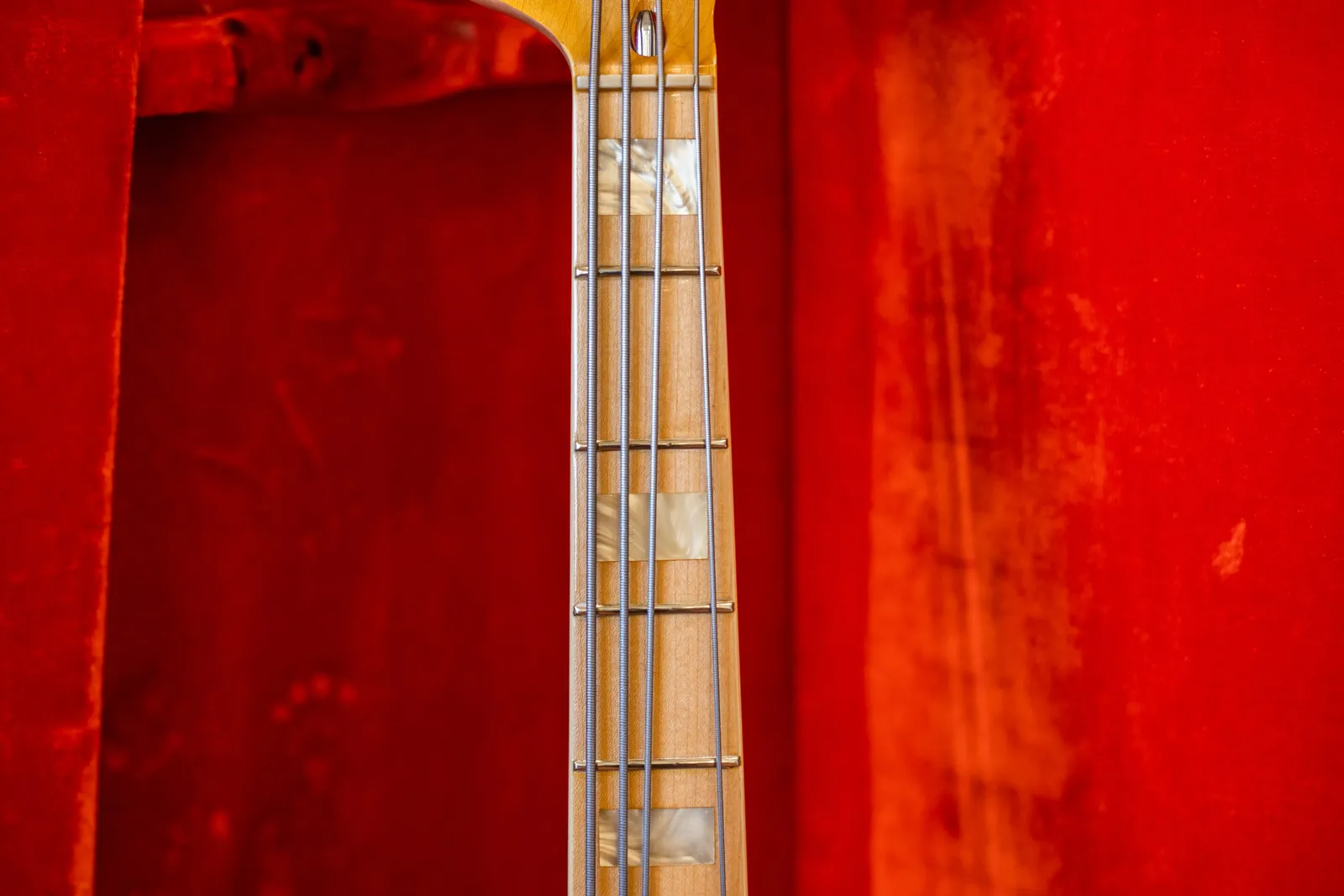Close up of the maple fingerboard on a 1976 Fender Jazz Bass with white pearloid block inlays, in a red lined case