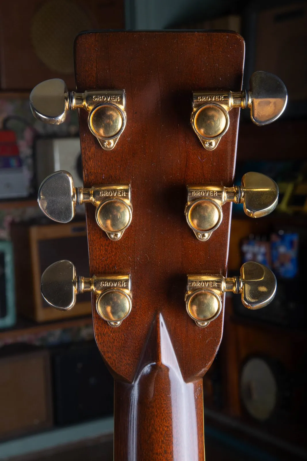 Back of the headstock of a 1976 Martin 000-45 showing six gold Grover enclosed tuners stamped GROVER, mounted on a mahogany neck and headstock.