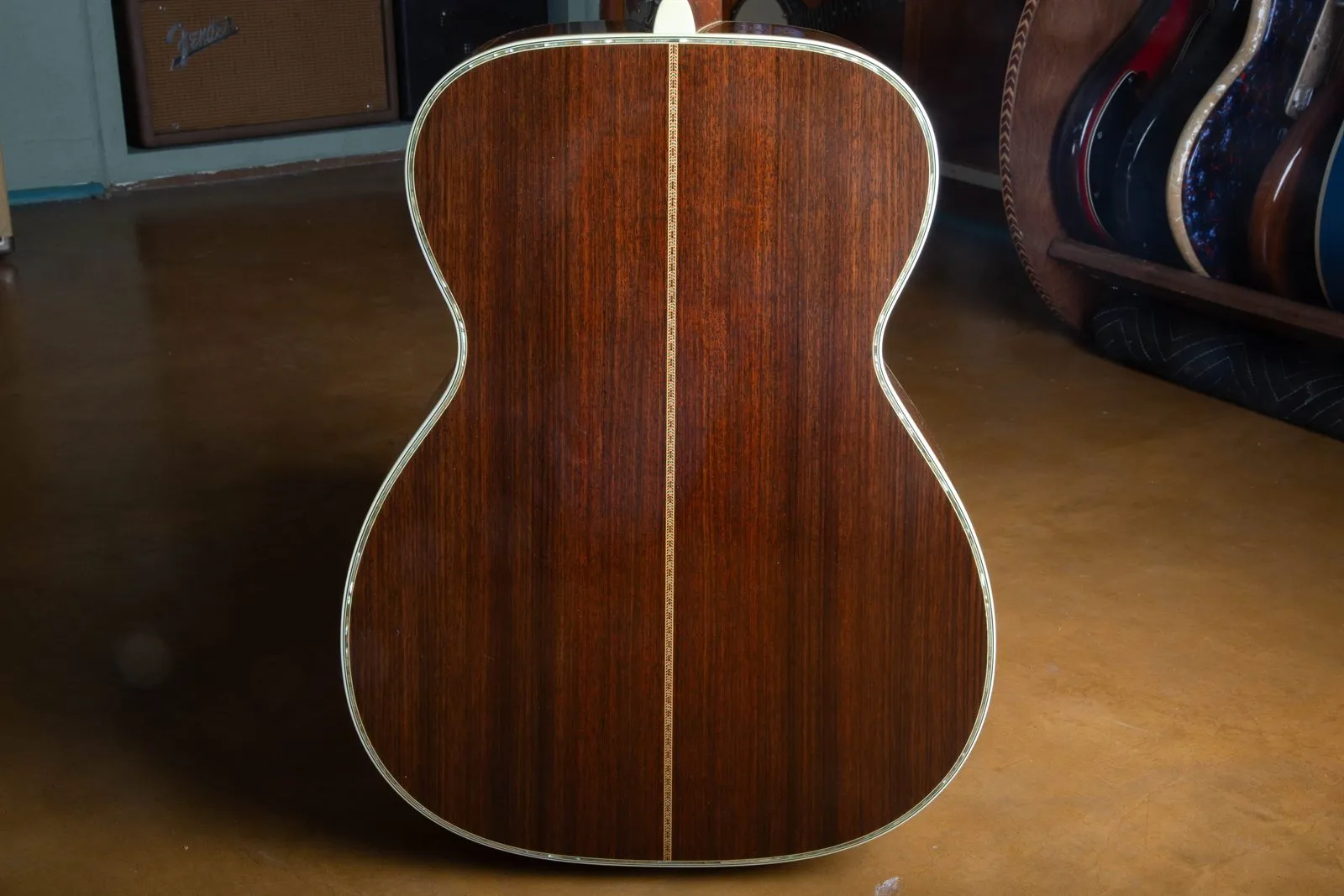 Back of a 1976 Martin 000-45 showing the two-piece East Indian rosewood back, abalone pearl border around the full perimeter, ivoroid binding, and the multi-color zipper backstrip down the center seam.