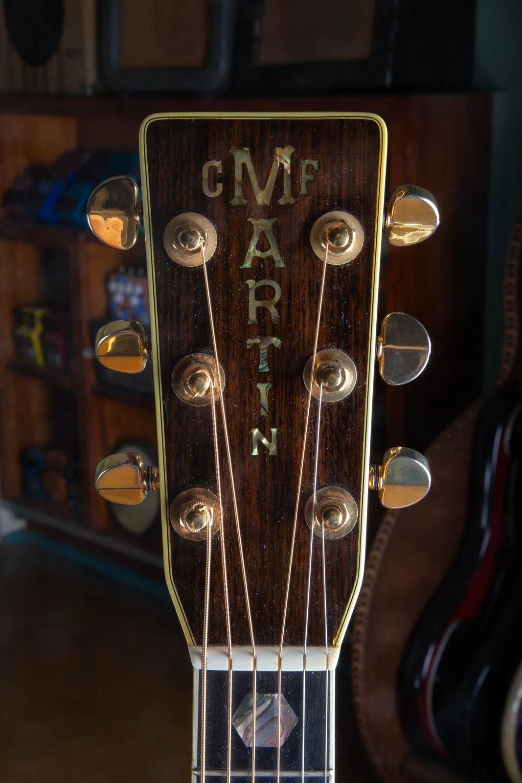 Headstock of a 1976 Martin 000-45 showing the vertical pearl C.F. Martin block-letter inlay on a bound rosewood face, gold Grover tuners, and an abalone hexagon inlay at the first fret.
