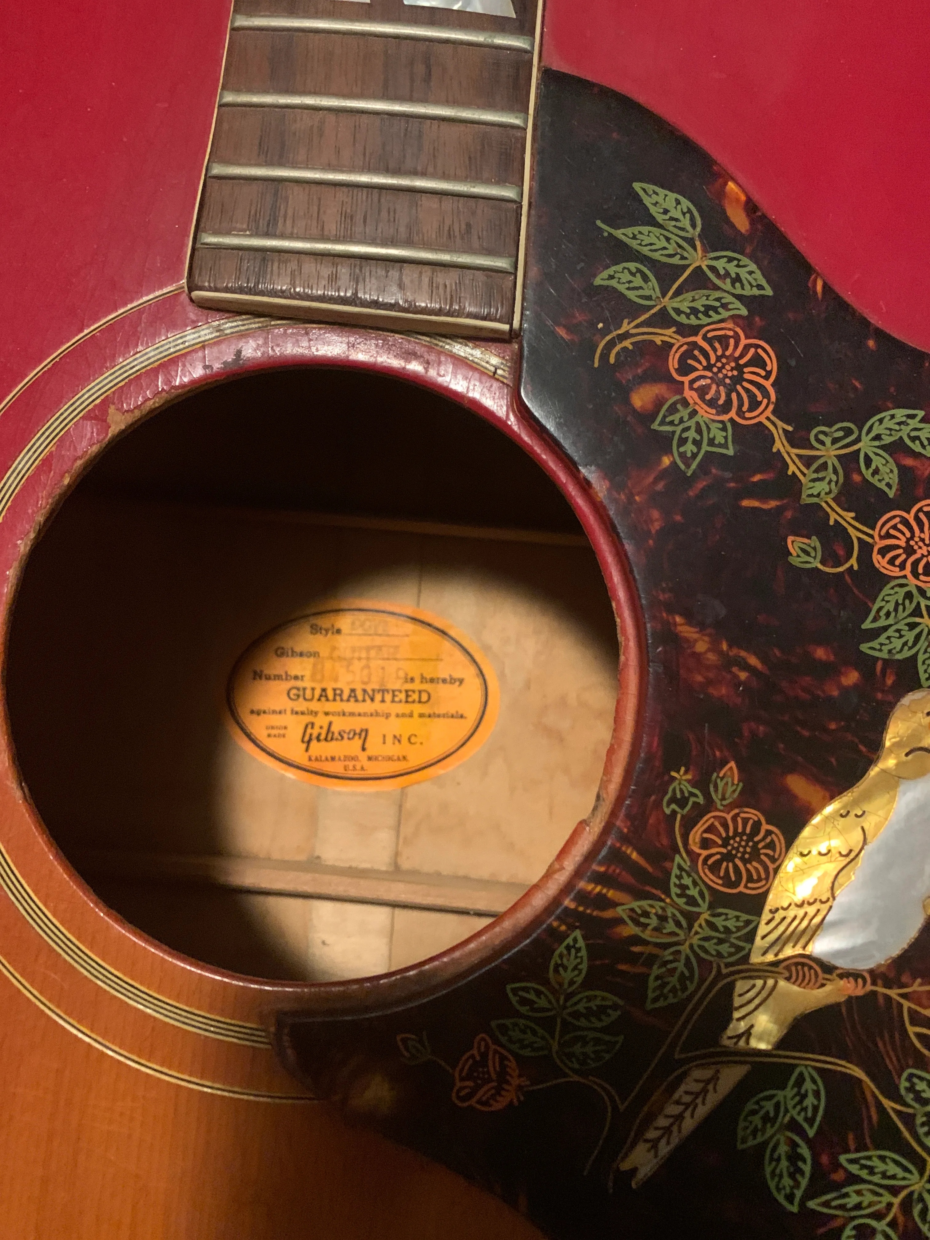 Orange Gibson Dove label numbered 845019 inside a guitar with a red-finished top