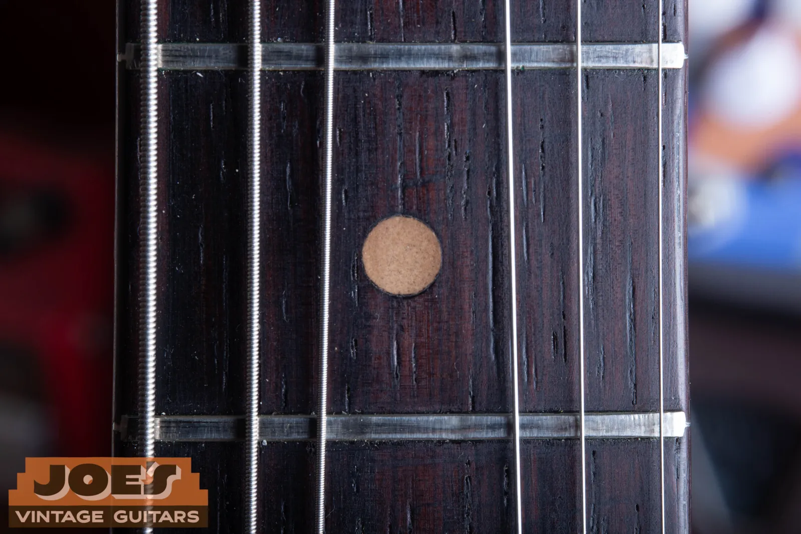 A clay dot inlay on a Fender Jazzmaster fingerboard, light brown and completely matte