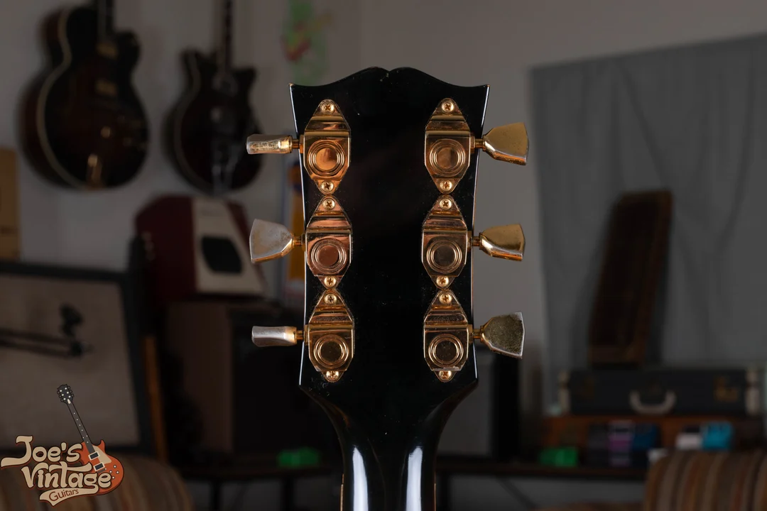 Gold Kluson Sealfast tuners on the back of a black Gibson headstock