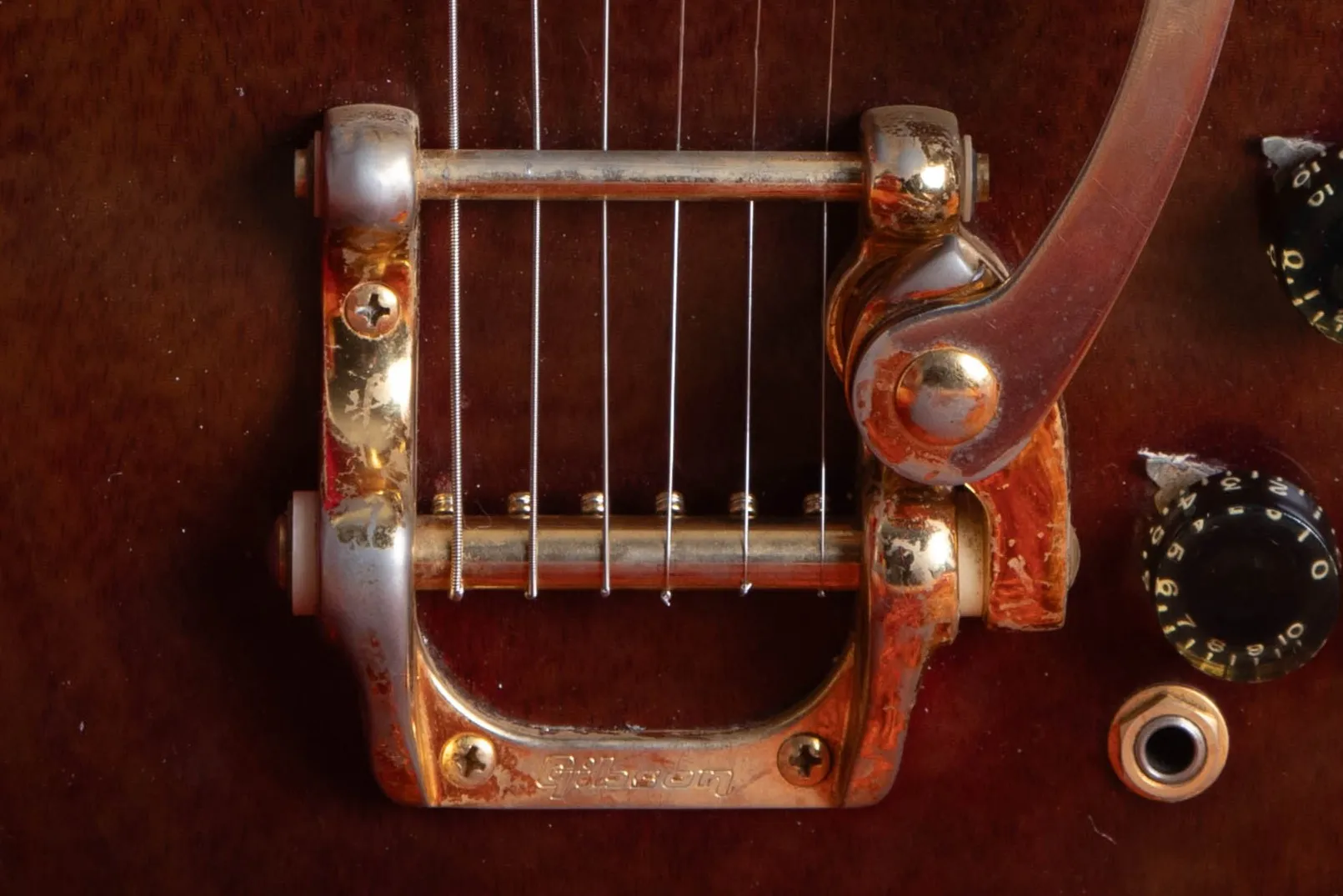 Gold Bigsby tailpiece with visible plating wear on a walnut SG Custom