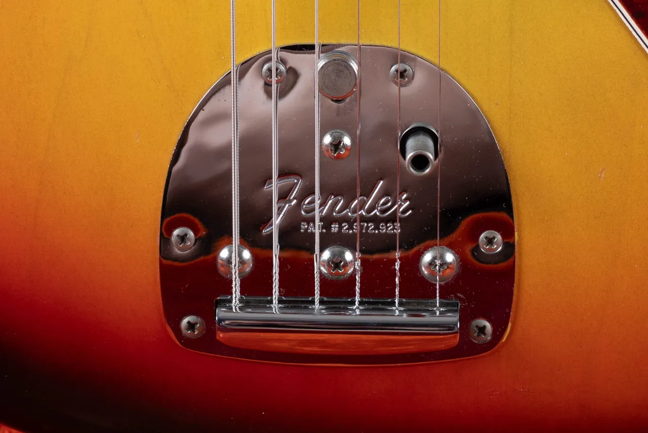 The floating tremolo of a Fender Jazzmaster showing the trem-lock thumb button and the arm socket