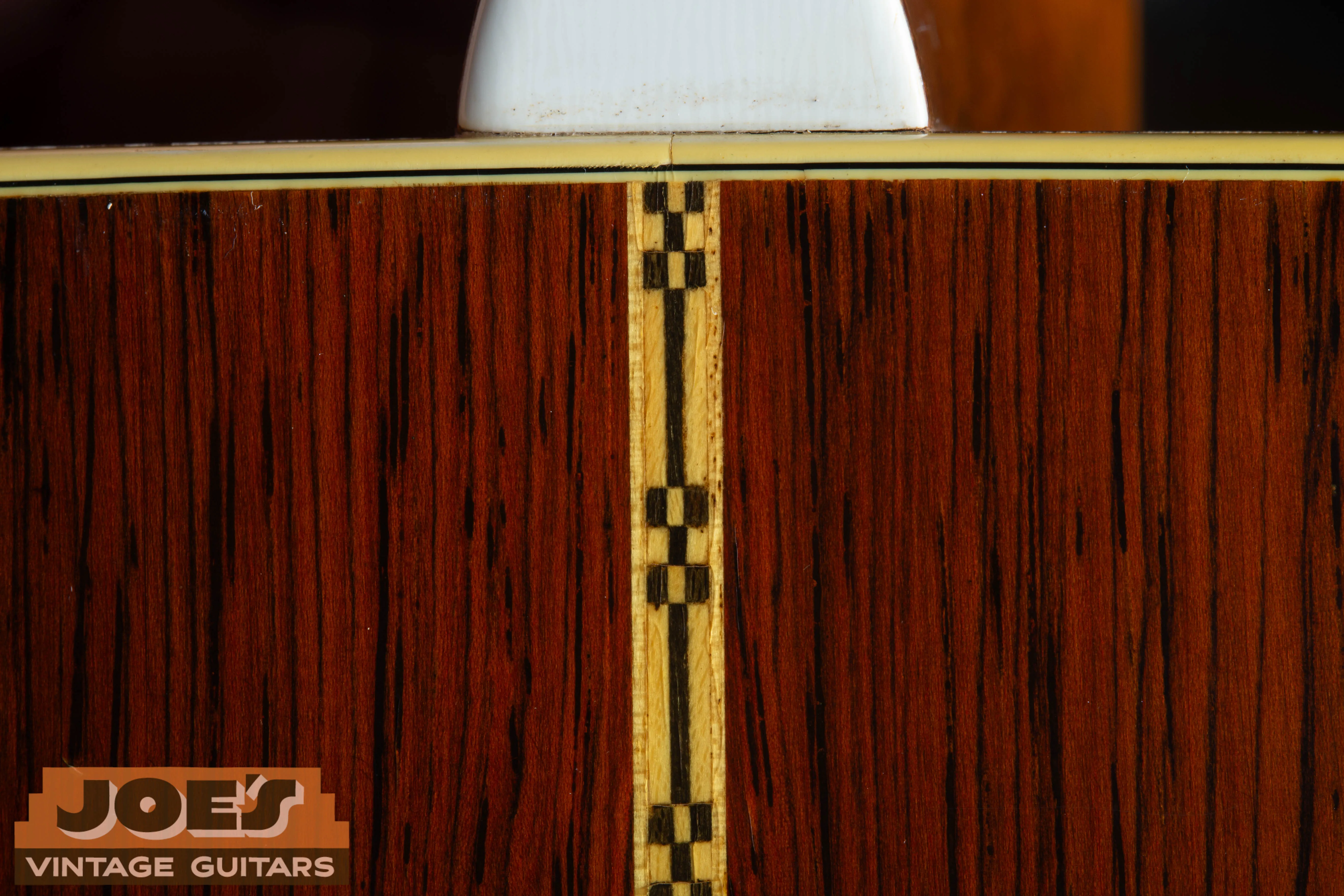 Close-up of the vintage “checkerboard” or Z-pattern backstrip on a 1959 Martin D-28E with Brazilian Rosewood. This decorative mosaic strip is a hallmark of the D-28E and is notably absent on the mahogany-backed D-18E.