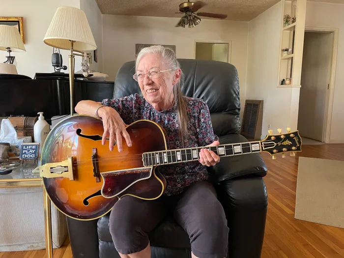 The original owner's daughter holding her father's 1954 Gibson L-5C in her home