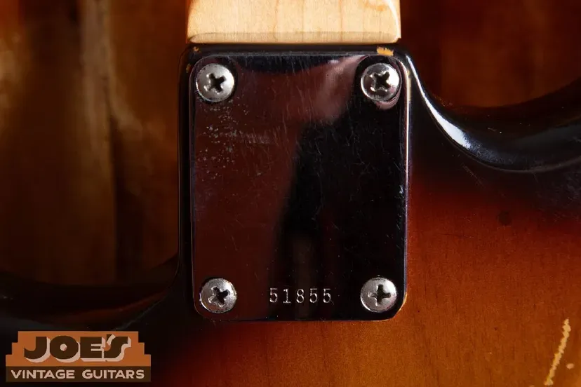Serial number 51855 stamped on a metal neck plate with the surrounding guitar body visible
